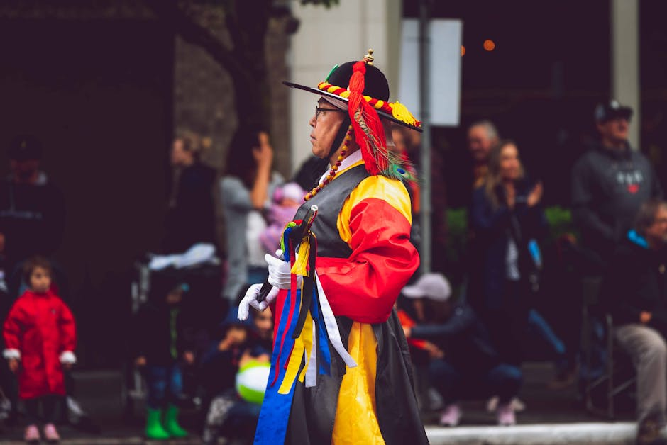 Man in traditional Korean attire during a vibrant street festival parade outdoors.